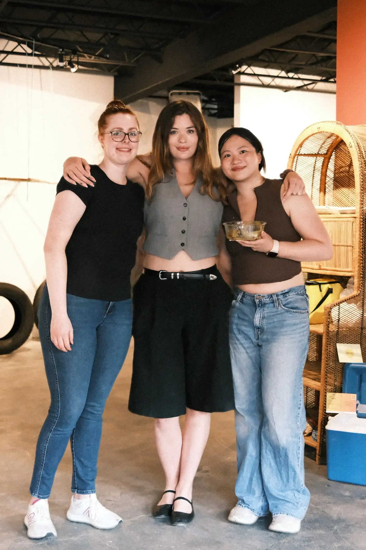 Three guests standing arm in arm at Sauté Sundays, one still holding the glass dish she brought to share