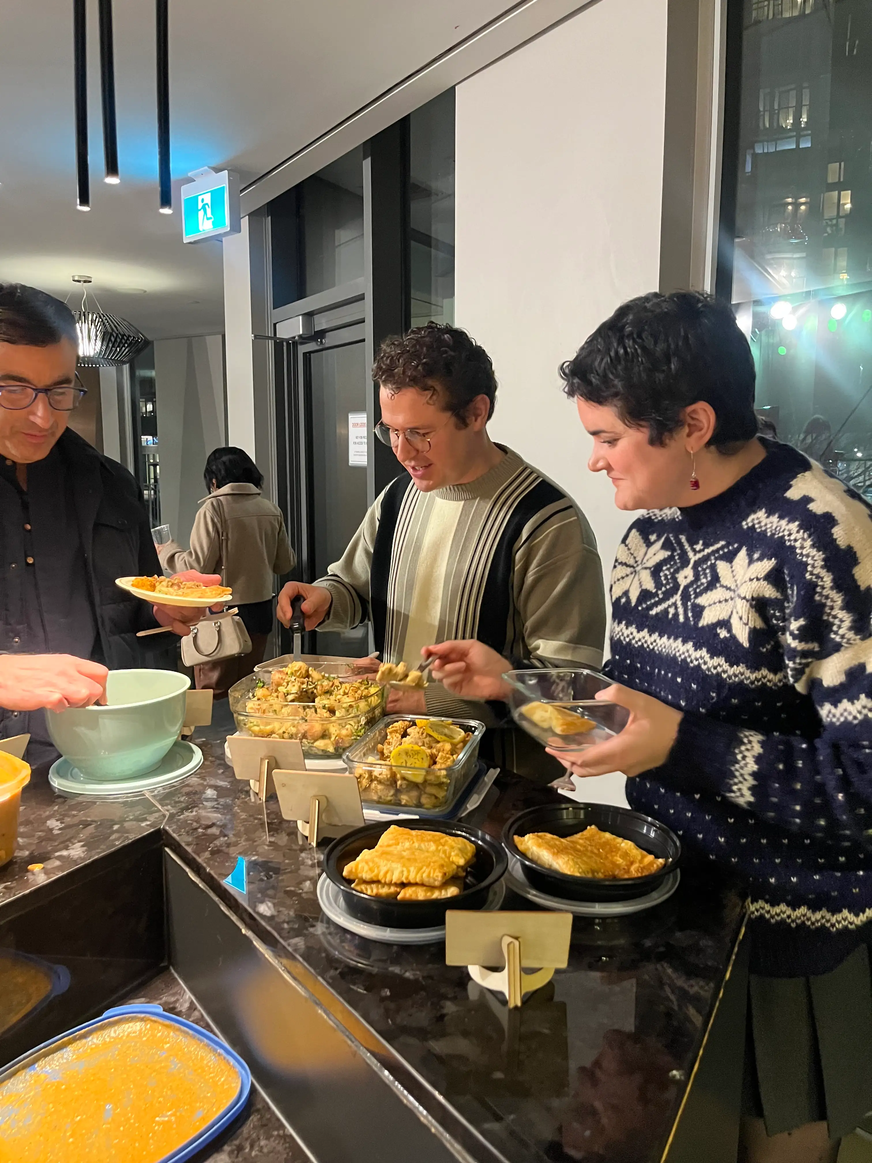 Guests helping themselves at the counter during Sauté Sundays, with pastries, dal and glass dishes spread along it