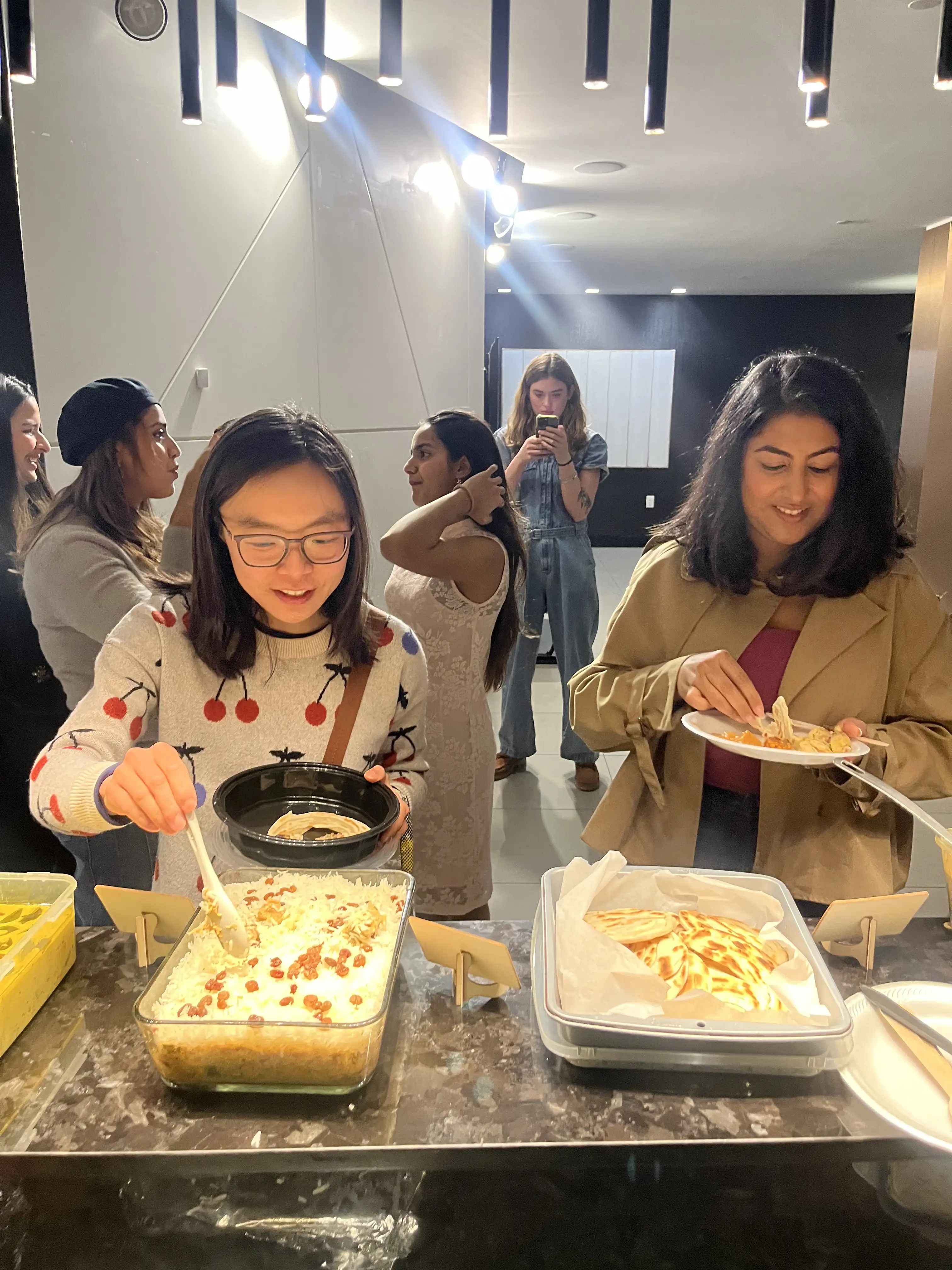 A guest serving herself rice while another lifts flatbread from a tray at Sauté Sundays