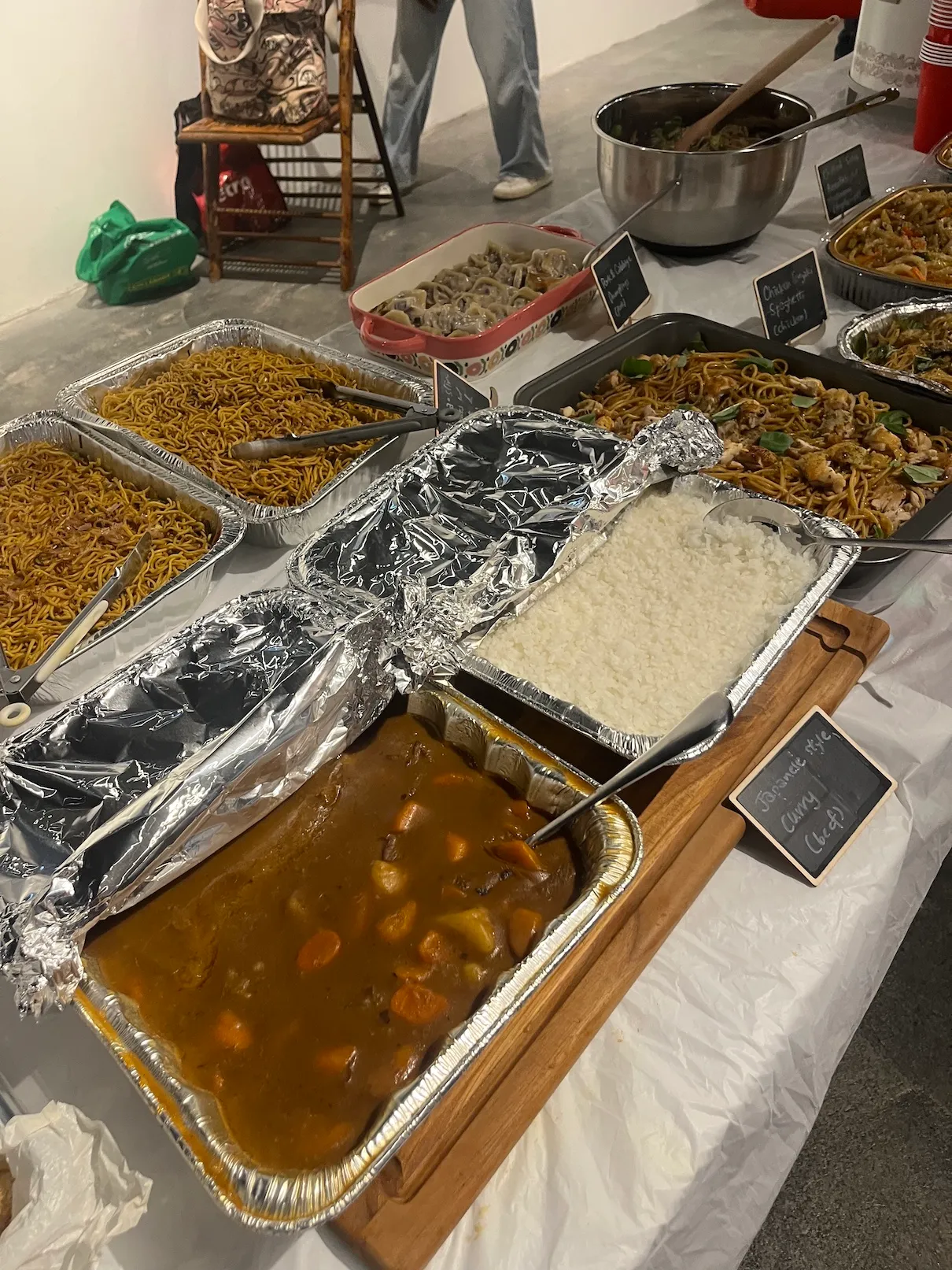 Trays of Japanese style beef curry, rice and fried noodles filling the end of the table