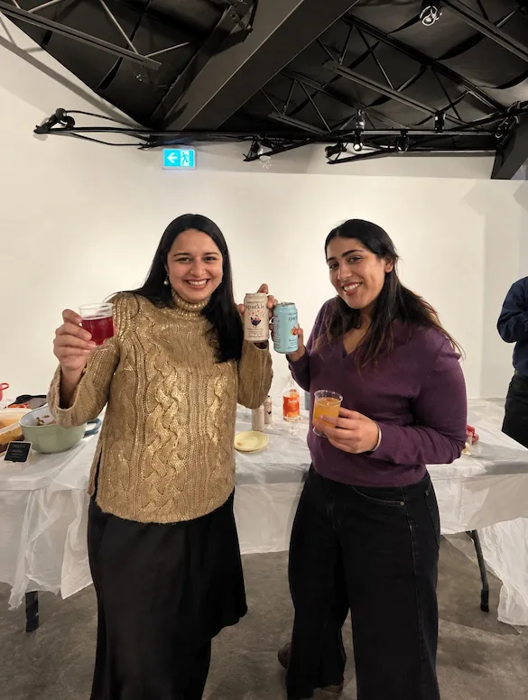 Two guests raising their mocktails at the bar, one holding a can of Heartwood Sparkle